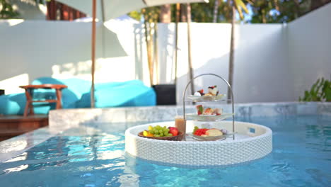 bandeja flotando en el agua de la piscina con comida para el desayuno