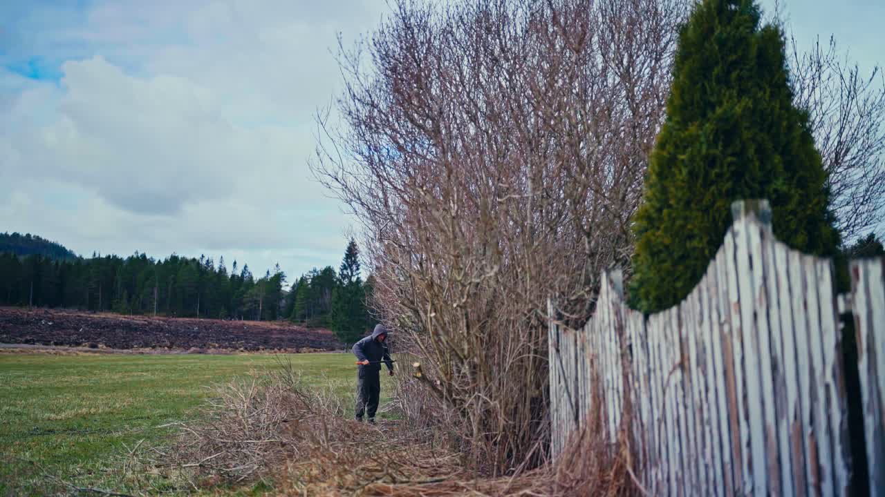 Time-lapse Of A Man Cutting Dried Trees In The Yard With A Wooden Fence