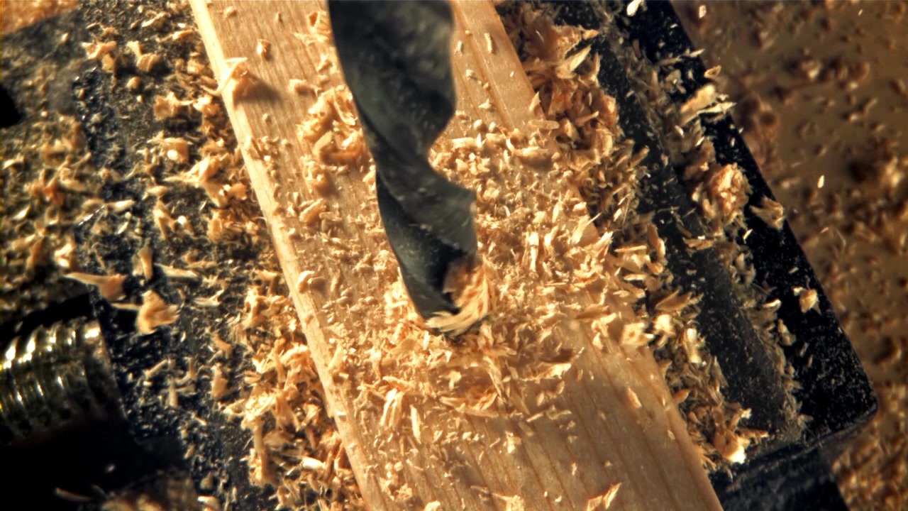 Close Up of Drill Bit Drilling into Wood, Creating Sawdust