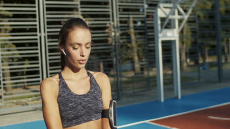 fitness girl with airpods doing squats at sport court on summer morning 1