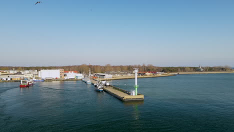 Red-Fishing-boat-enters-the-port-on-Hel,-clear-blue-watr-and-gulls-flight-on-clear-sky,-slow-motion