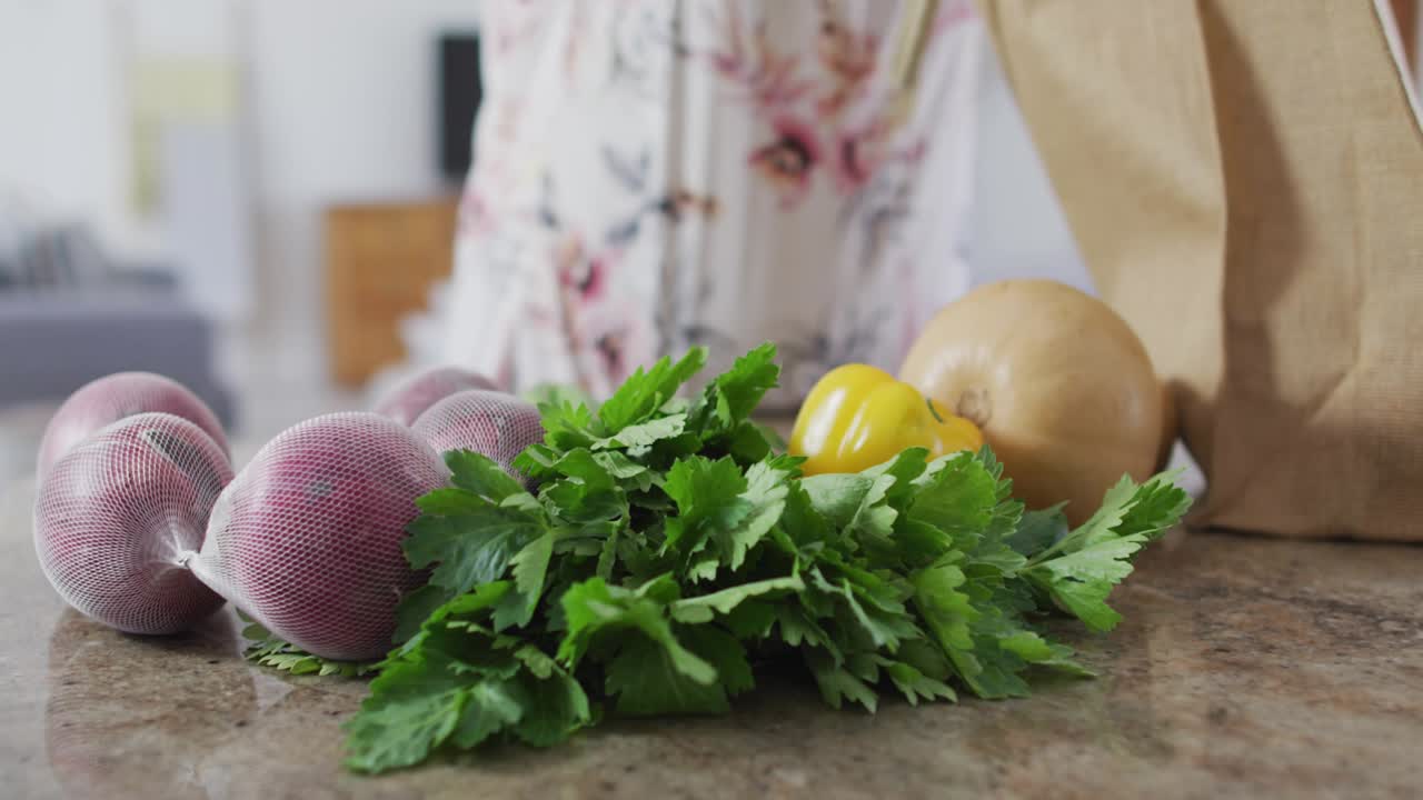 Numeric overlay initiating woman raising bag upright and unpacking green pepper for cooking prep
