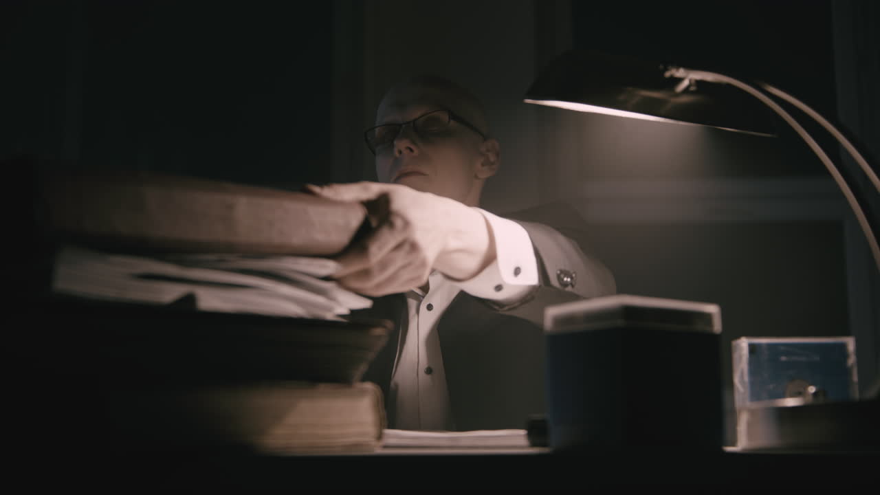 Un contabile pallido e calvo esamina i documenti fiscali nella stanza strana di notte.
