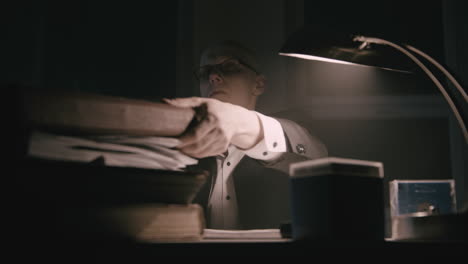 pale bald accountant looks through the tax papers in the weird room at night