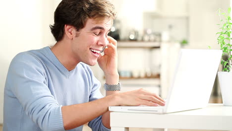 Hombre-Feliz-Hablando-Por-Teléfono-Celular-Usando-Una-Computadora-Portátil