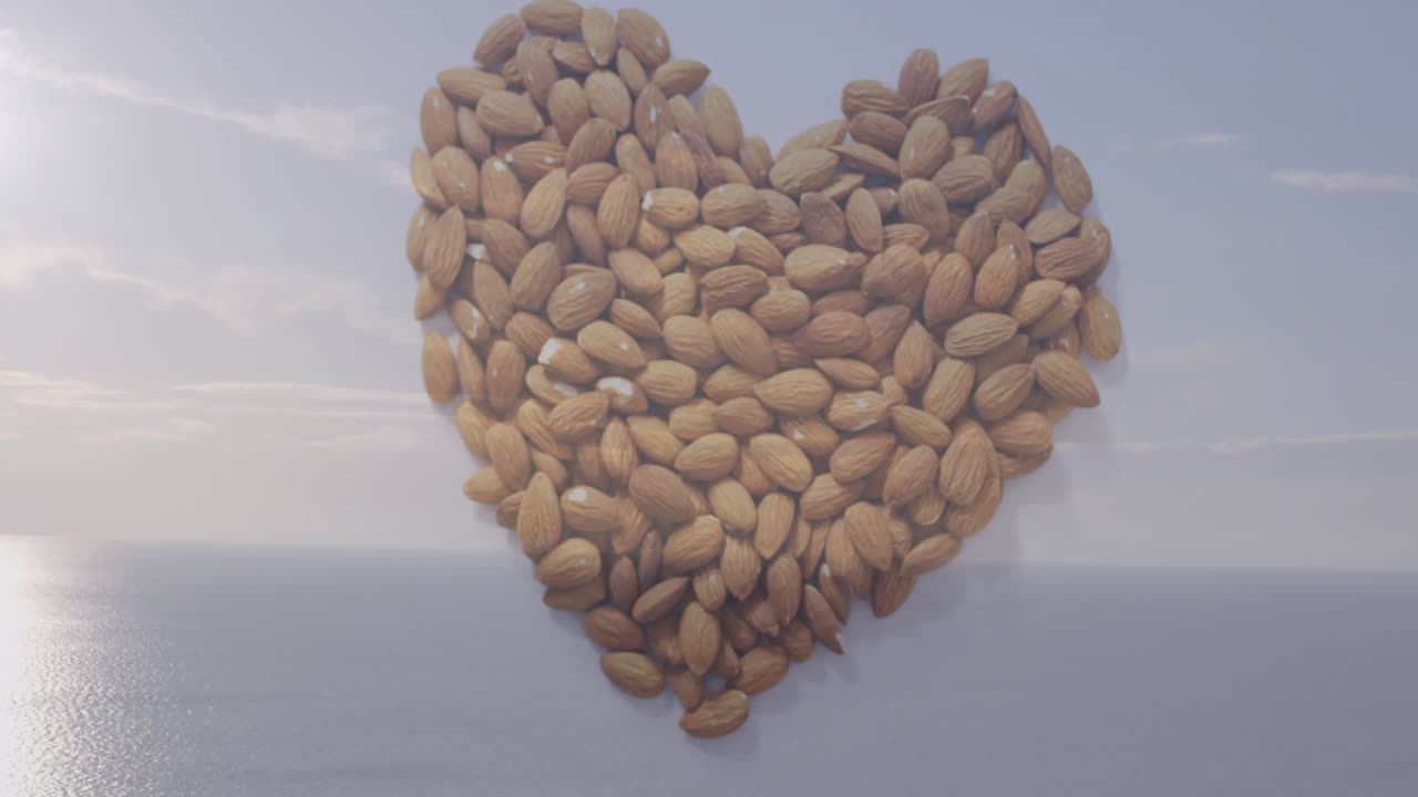 Arranged in heart shape, almonds over serene ocean background creating animation