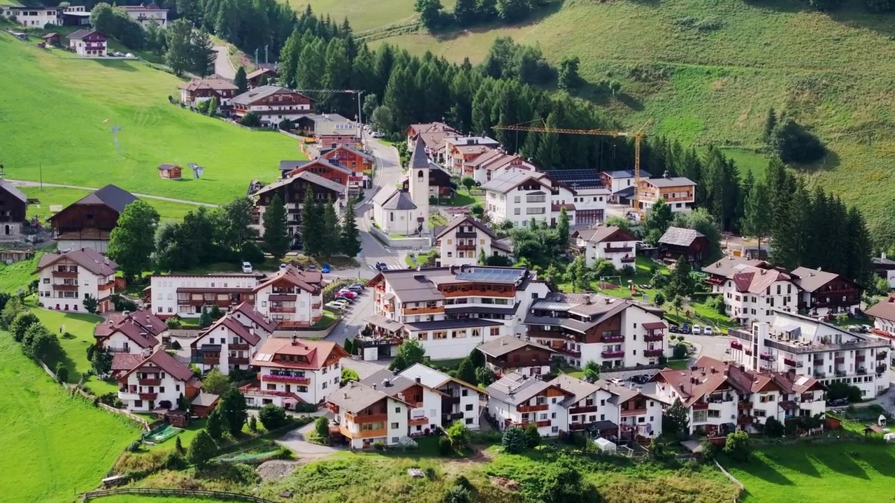 Luftaufnahme von Antermoia – friedliches Bergdorf umgeben von grünen Feldern.