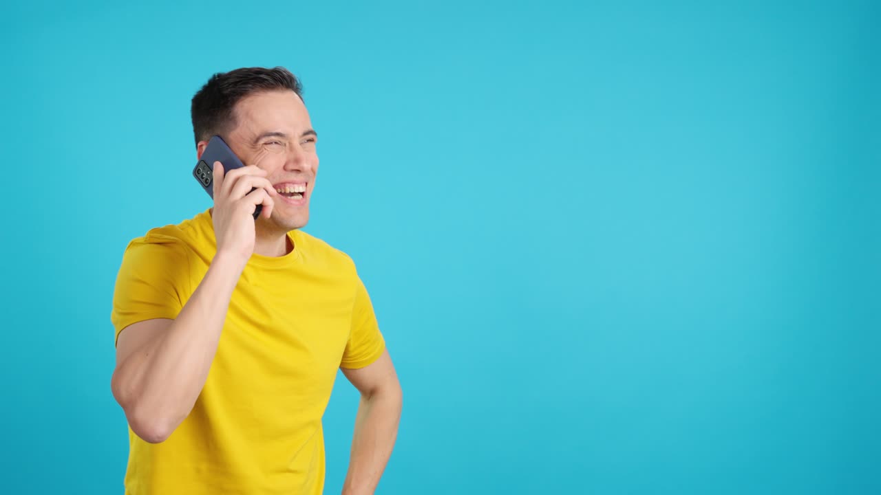 Man talking on phone in yellow shirt on blue background