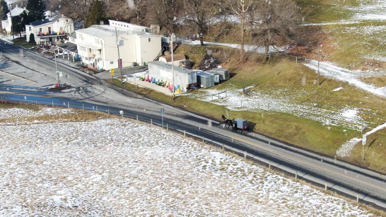 AERIAL Horse-Drawn Carriage Trotting Into Rural Township While Snow Falls