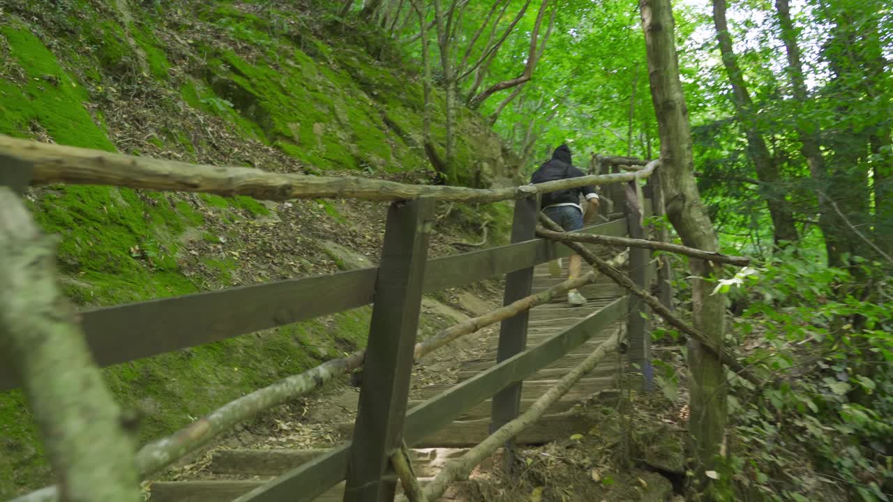 숲 속의 계단에서 달리는 젊은 남자.