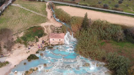 in saturnia italy, the drone rises up while tilting down revealing the entire hot spring baths