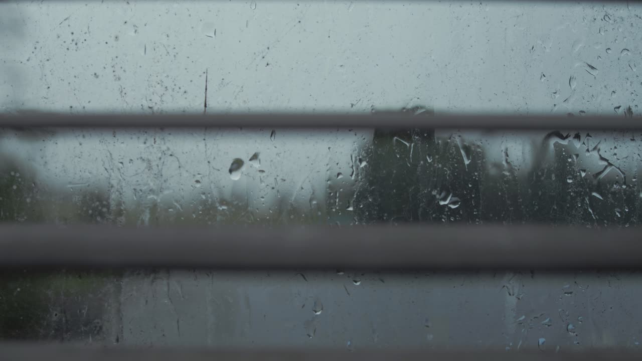 Raindrops rolling down window looking through blinds