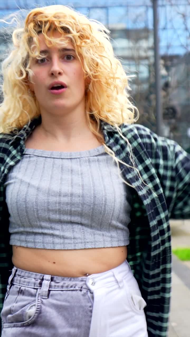 Woman with blonde curly hair and flannel shirt in an urban setting