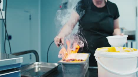 Señora-Cocinando-Helado-Flambeado-En-Una-Cocina-Industrial