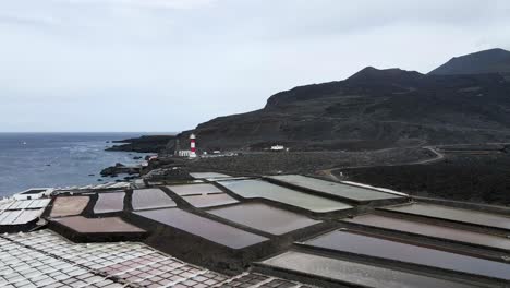 drone aerial footage of salinas de fuencaliente on the volcanic island of la palma with a lighthouse on a cloudy day