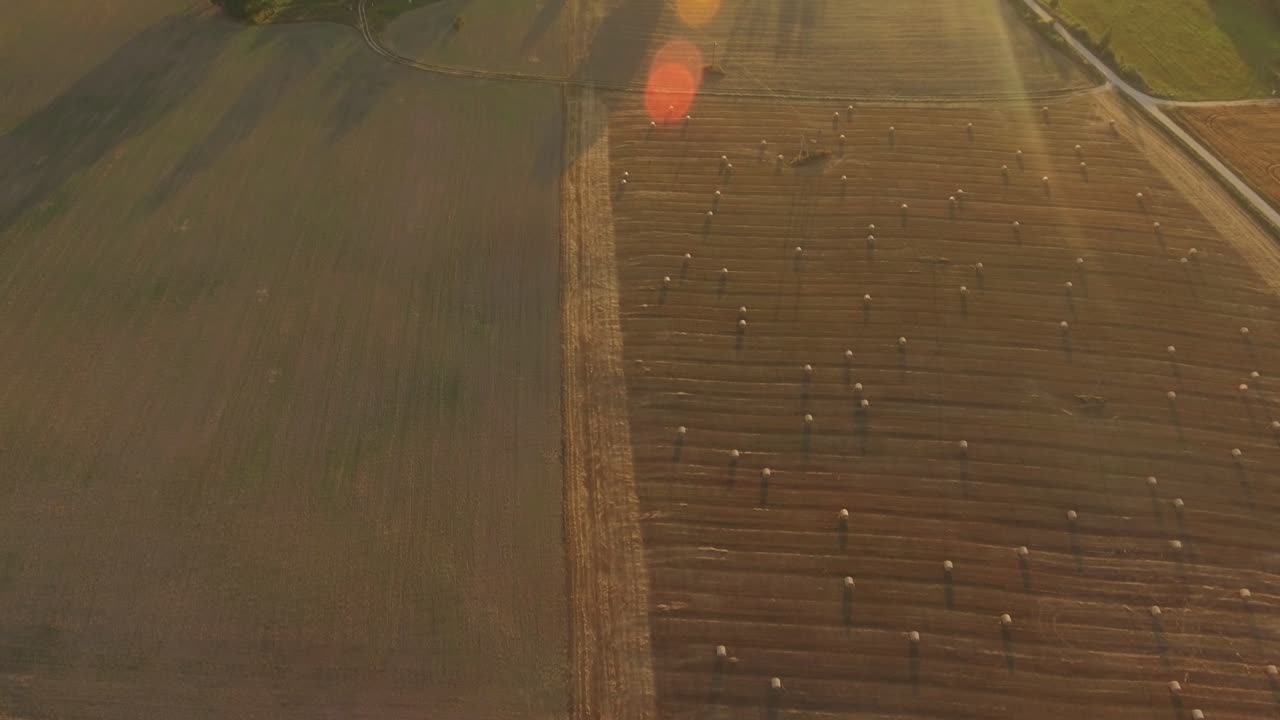 Hay Rolls In Harvested Agricultural Fields On A Sunny Evening At Sunset. Aerial Dolly-In Tilt-Up