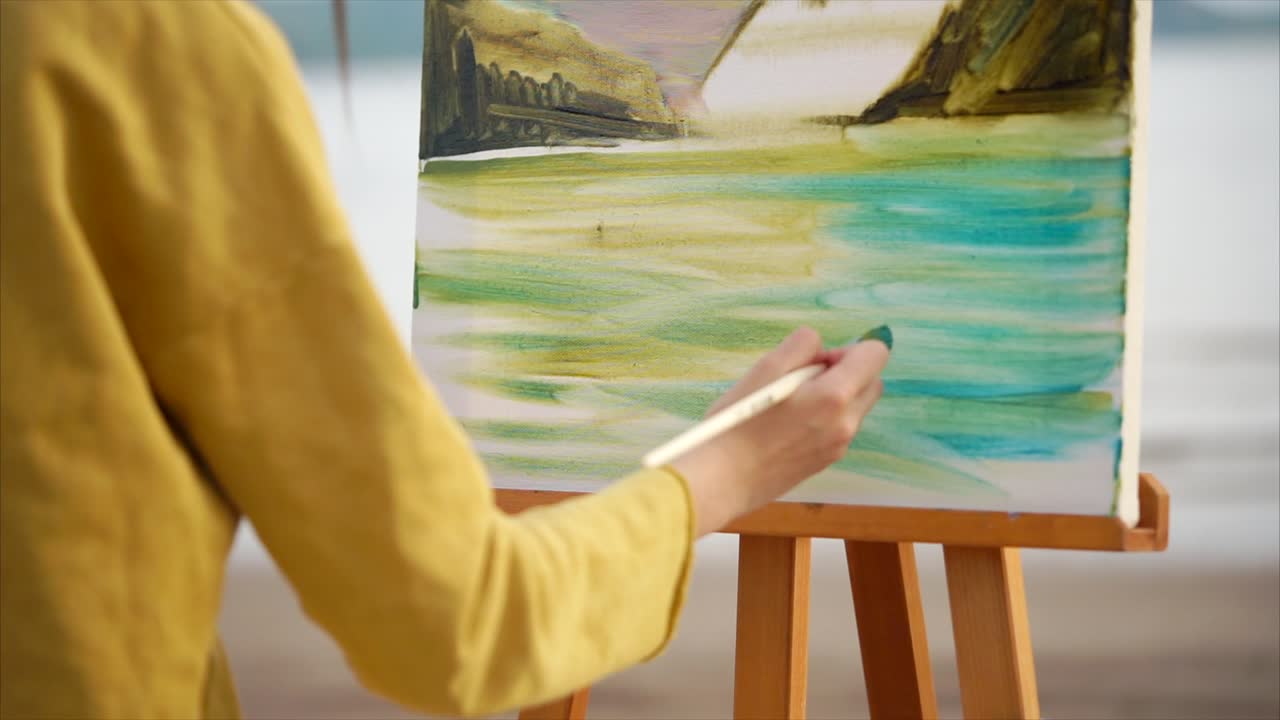 Woman painting a landscape on the beach