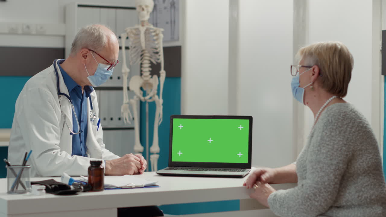 Doctor and retired patient using laptop with greenscreen