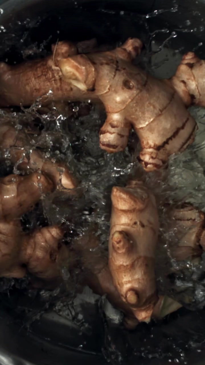 Acqua che scorre su radici di zenzero fresco al rallentatore