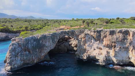 discover the breathtaking beauty of cala varques, a serene coastal spot in porto cristo, majorca. enjoy the clear blue waters and natural rock formations surrounded by lush greenery.