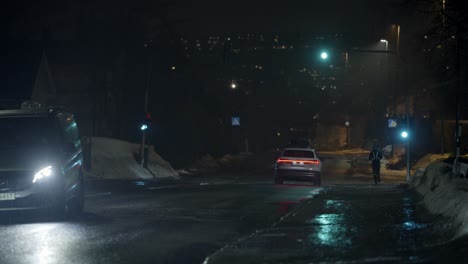 busy car and trafficlights reflecting on rainy and slippery ice pavement. tilt up movement.