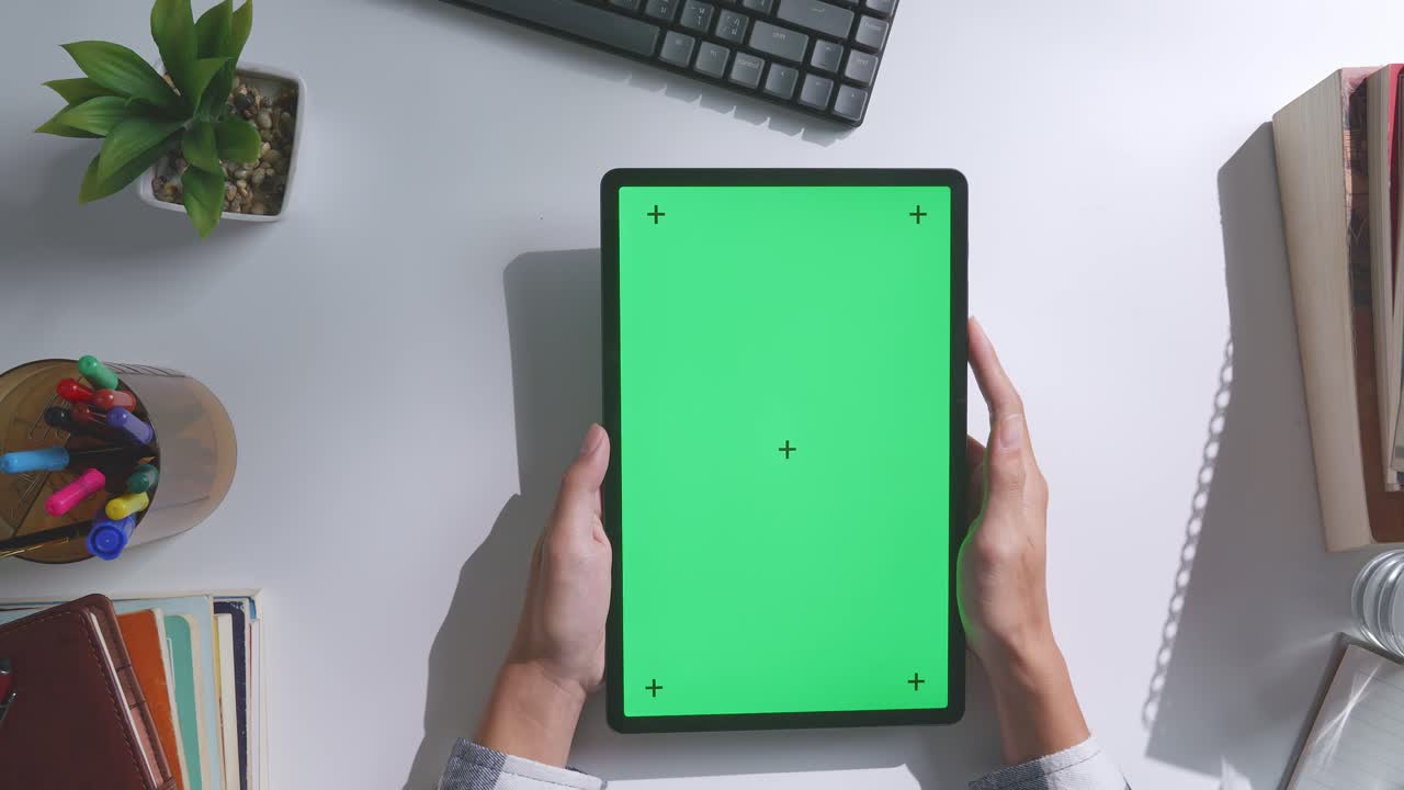 초록색 화면을 모방한 노트북 컴퓨터의 상단에서 아래로 볼 때, 펜, 안경, 그리고 물 한 잔을 가진 노트북 에 나무 사무실 책상 위에 크로마키 디스플레이가 있습니다.