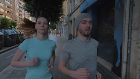 a young couple jogging on a paved sidewalk