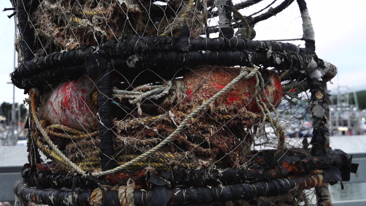 Un gros plan d'une pile de casiers à crabes dans un port avec des bateaux en arrière-plan