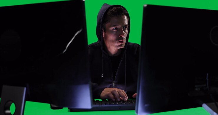 Caucasian man working on computers on green background
