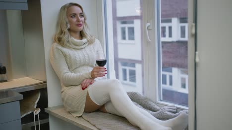 woman drinking wine near window