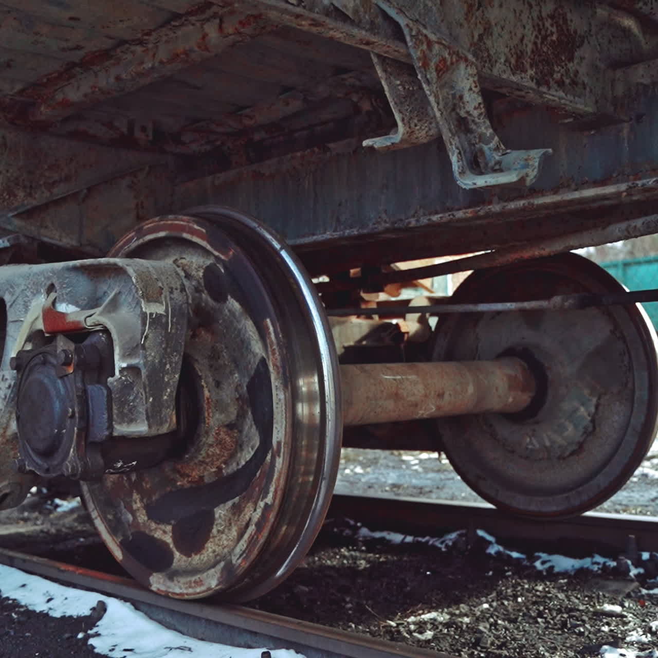 View of the rusty bottom of the container, which moves along the rails on the railway in the winter. Close-up