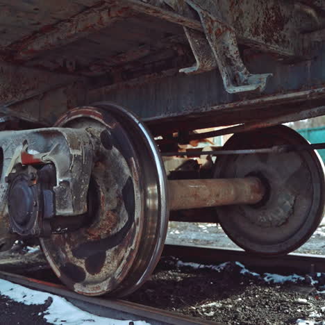 view of the rusty bottom of the container, which moves along the rails on the railway in the winter. close-up