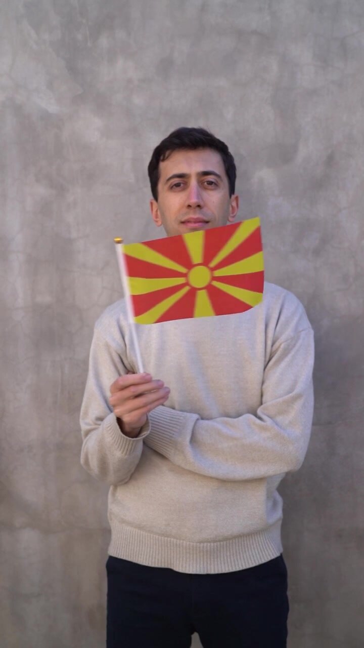 Uomo che sventola la bandiera macedone. Ripresa verticale al rallentatore.
