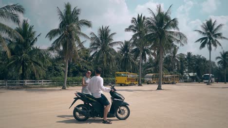 woman kisses man sitting on motorcycle girl waves hand