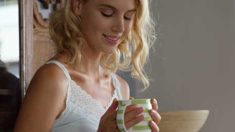 una rubia linda tomando café en la cocina.