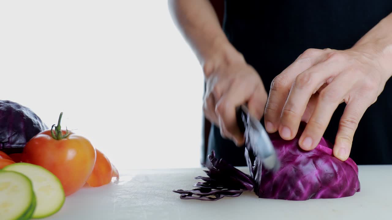 4K Women Hand cutting fresh red cabbage on Cutting Board. Female hand slices raw red cabbage into little slide with knife on cutting Board. healthy food concept.