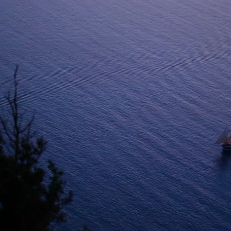 A-beautiful-sailing-ship-sails-near-a-coastline-at-night