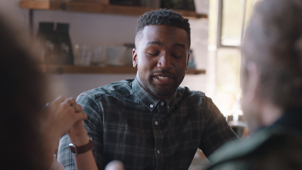 uomo afroamericano felice che passa il tempo con gli amici in un caffè a chiacchierare a condividere conversazioni a bere caffè a socializzare a divertirsi a incontrarsi al ristorante