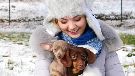 mujer jugando con sus perros pequeños fuera del invierno