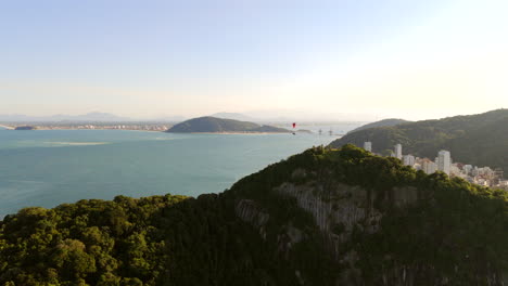 dramatic upward drone fly above the morro do boi touristic peninsula to seen distant matinhos and guaratuba municipality, paraná, brazil