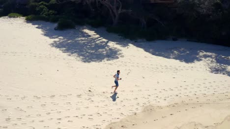 chico descalzo corriendo en la costa arenosa en la playa de verano cerca del campamento de la era norte en el parque nacional real, nsw, australia