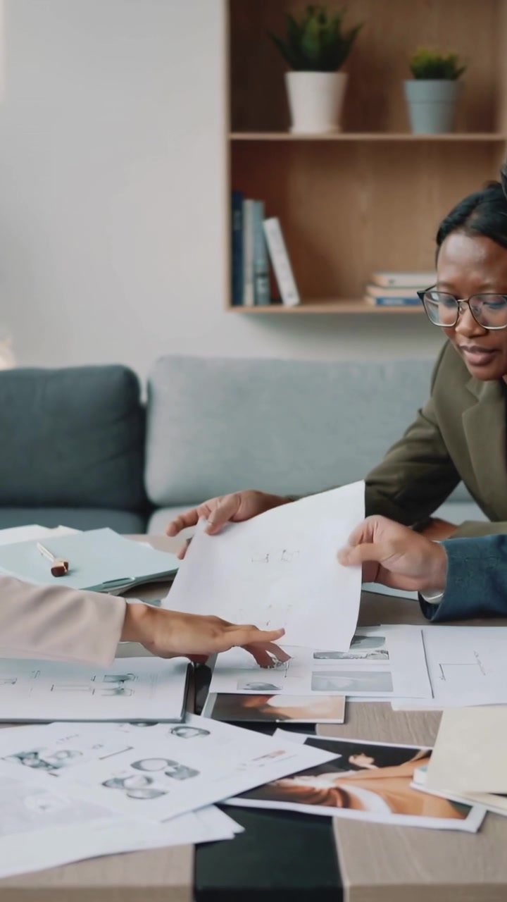 Vertical video: Mockups on table urging woman in blazer sorting sheets to pick layouts in office