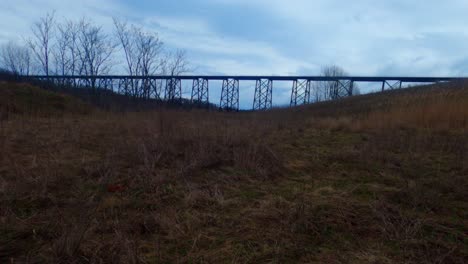 Ein-Bewölkter-Zeitraffer-In-Den-Appalachen-Mit-Einem-Zug,-Der-Auf-Einem-Viadukt-Im-Hintergrund-Und-Einem-Felsbrocken-Im-Vordergrund-Vorbeifährt