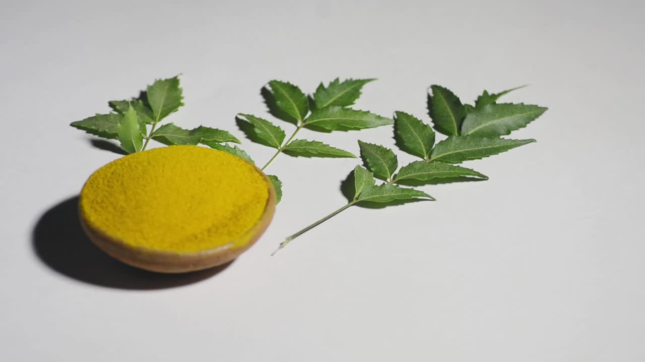 Medicinal turmeric powder  with neem leaves over white background