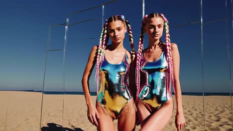 beach models posing in metallic swimwear, sporting colorful braids, reflecting sunlight through mirrored surfaces against sandy coastal landscape, presenting futuristic aesthetic