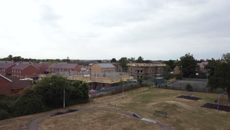 drone acercándose al sitio de desarrollo de la construcción mientras pasa sobre un árbol en un parque desde un ángulo medio en bedfordshire, inglaterra, reino unido, en un día nublado
