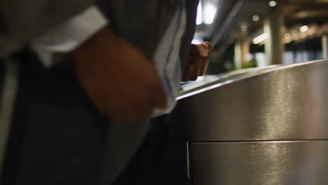 midsection of african american businessman arriving in modern office through security gates