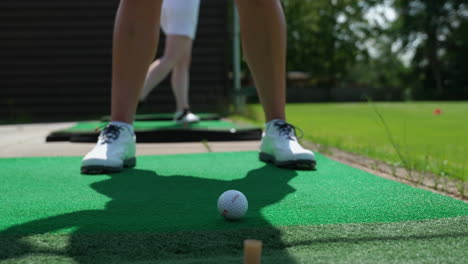 Niedrige-Winkelansicht-Der-Füße-Eines-Golfers,-Der-Seinen-Schwung-Ausführt-Und-Den-Ball-Aus-Nächster-Nähe-über-Das-Fairway-Schlägt