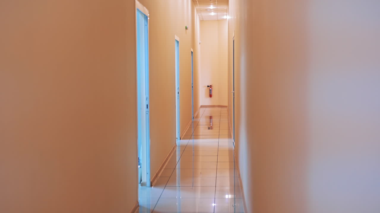Back view of a man in protective suit and with bag going through the corridor. Male worker is carring out special bag with test tubes from the laboratory.