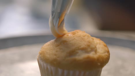 Tragen-Sie-Cremigen-Zuckerguss-Auf-Einen-Vanillemuffin-Auf